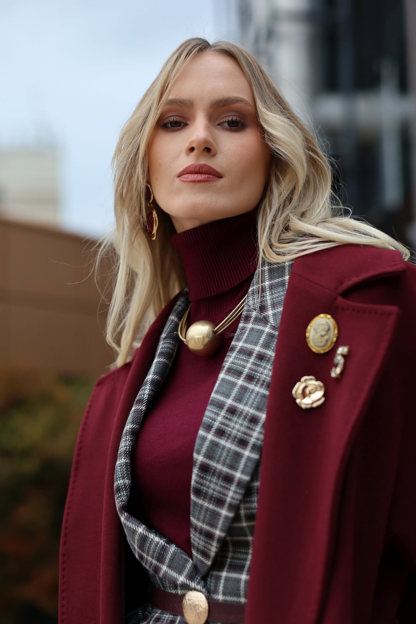 Portret VICTORIA cu broșe de epocă aurii pe reverul paltonului bordo.
